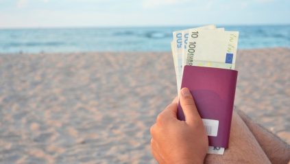 Turysta trzymający paszport i pieniądze na plaży