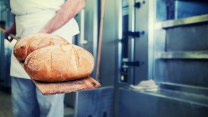 Piekarz wkładający chleb do pieca w piekarni