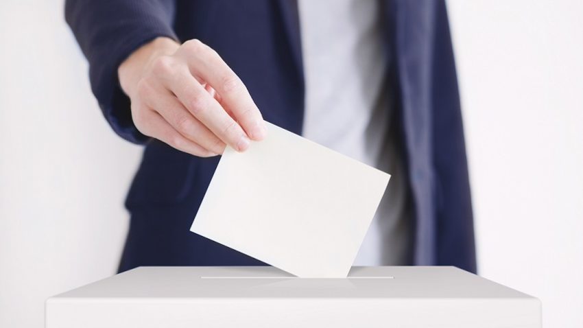 Ręka wrzucająca kartkę z głosem wyborczym do urny