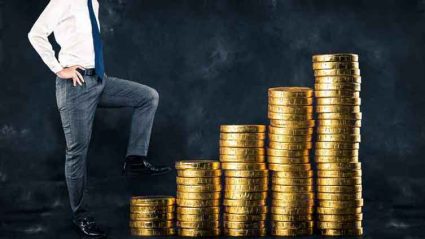 Grafika ilustracyjna: Pracownik wspinający się po stosie pieniędzy