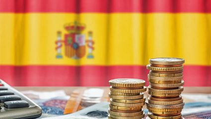 Pieniądze i kalkulator na tle hiszpańskiej flagi
