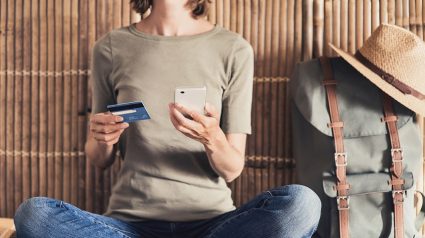 Kobieta ze smartfonem, karta płatniczą i plecakiem podróżnym