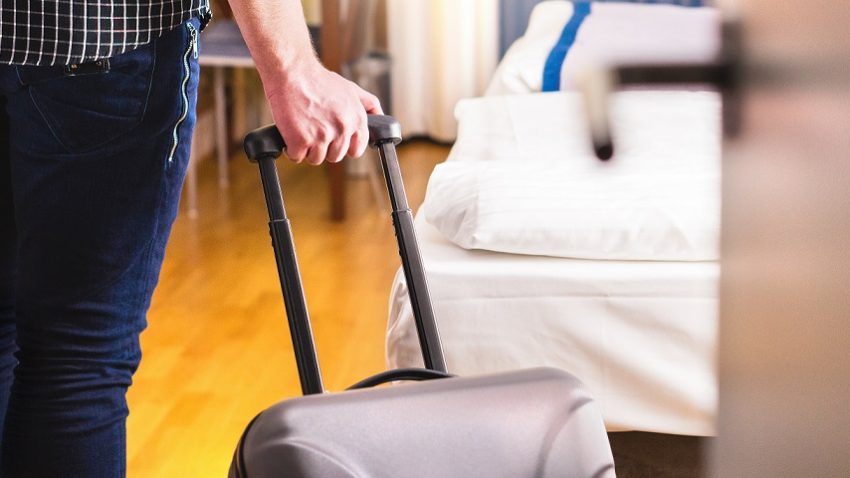 Mężczyzna w alizką stojący przy wejściu do pokoju hotelowego