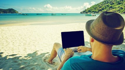Mężczyzna pracujący na komputerze na plaży