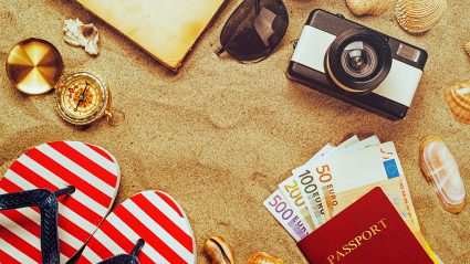 Pieniądze, paszport, klapki i aparat na plaży