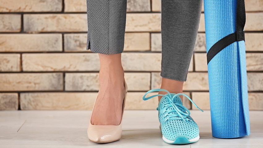 Stopy kobiece: na jednej but sportowy, na drugiej szpilka oraz mata do ćwiczeń sportowych