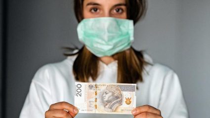 Kobieta w maseczce trzymająca pieniądze