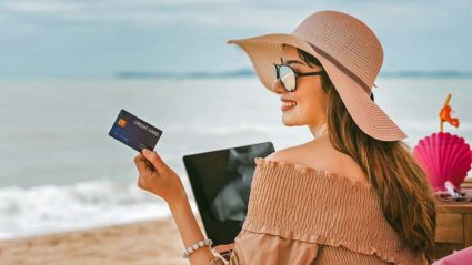 Kobieta na plaży z kartą kredytową przed komputerem