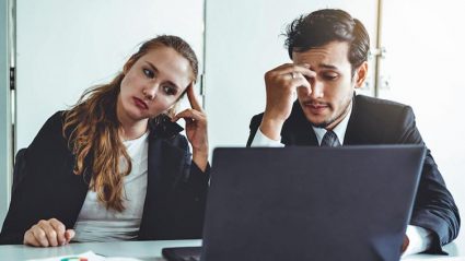 Dwoje smutnych ludzi w biurze przed komputerem