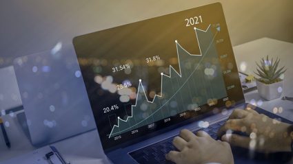 Mężczyzna przy komputerze patrzący na wykres gospodarczy z prognozami na 2021 rok