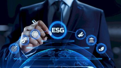 ESG napis wirtualny na tle kuli ziemskiej, na który wskazuje długopisem biznesmen