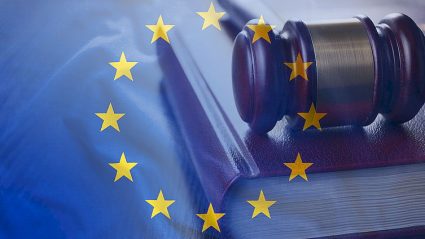kodeks, młotek sędziowski na tle flagi UE
