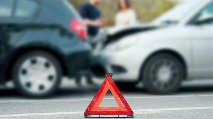 Trójkąt ostrzegawczy na drodze na tle wypadku samochodowego