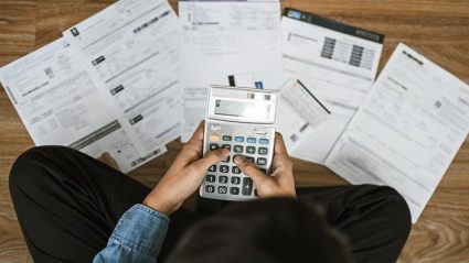 Mężczyzna siedzący nad rachunkami z kalkulatorem