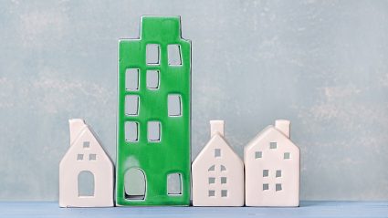zielona makieta wieżowca, trzy małe domy nie-zielone