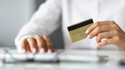 człowiek trzymający kartę płatniczą w dłoni, klawiatura komputera