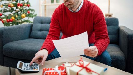 Smutny mężczyzna z kalkulatorem i świątecznymi prezentami
