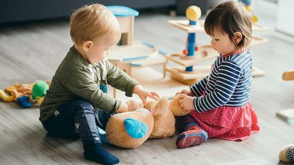 chłopiec i dziewczynka na dywanie z zabawkami