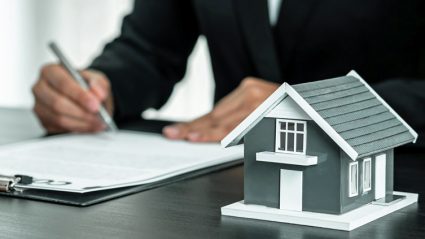 Dom i mężczyzna podpisujący umowę kredytu hipotecznego