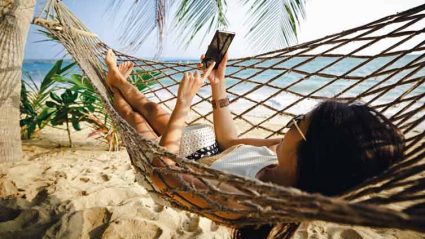 Kobieta korzystająca z telefonu w hamaku na plaży