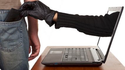 laptop, z ekranu ręka w rękawiczce, wyjmuje portfel z kieszeni mężczyzny
