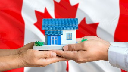 flaga Kanady, makieta domu, trzymana w dłoniach kobiety i mężczyzny