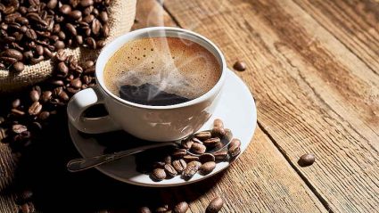 filiżanaka kawy, obok woreczek z kawą, ziarna