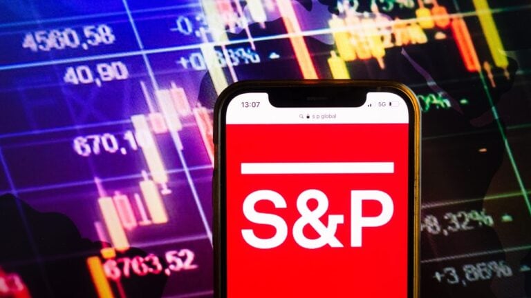 napis na smartfonie S&P, na tle ekranu z notowaniami