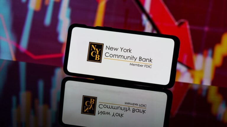 smartfon z napisem i logiem New York Community Bankcorp, NYCB, czerwony wektor w dół